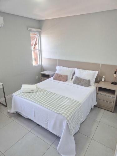 a bedroom with a large white bed with two pillows at Casa no segundo andar na Praia da Cal com ar e sacada in Torres