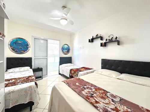 Un dormitorio con dos camas y un ventilador de techo. en Ap Frente Mar, wi-fi, piscina, pet, check-in e check-out flexíveis, en Praia Grande