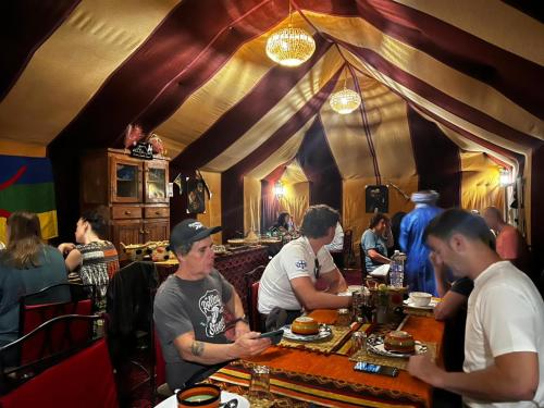 a group of people sitting at a table in a restaurant at Camp trip luxury in Merzouga