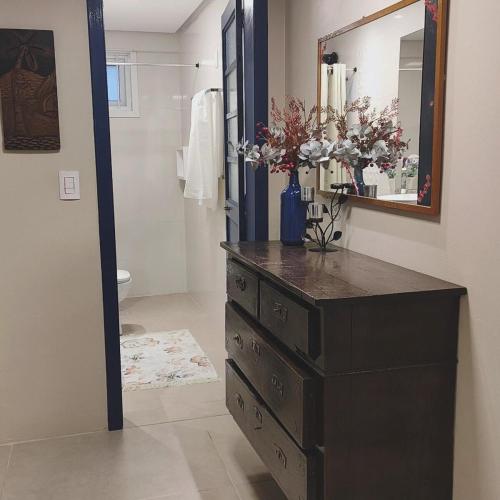 a bathroom with a dresser with a mirror and flowers at Casaloft994 in Bento Gonçalves