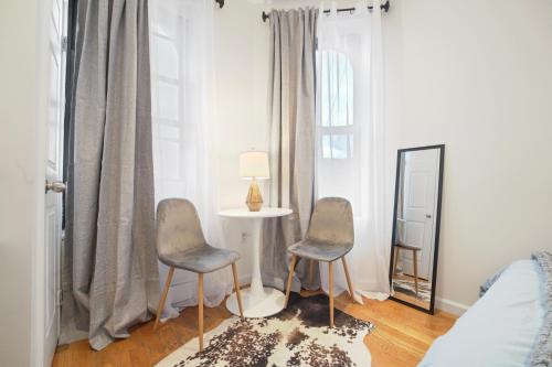 1 Schlafzimmer mit 2 Stühlen, einem Tisch und einem Spiegel in der Unterkunft 3BR Serene Suite Near Central Park in New York