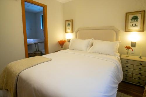 a bedroom with a large white bed with two pillows at Pousada Fazenda Aroeira Secretário in Itaipava