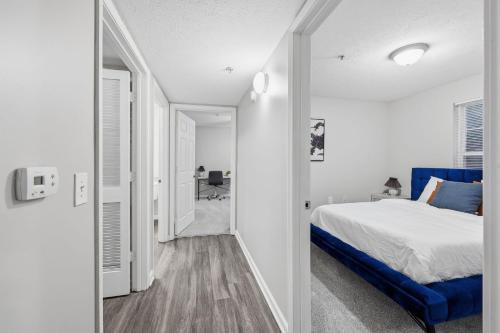 een witte slaapkamer met een blauw bed en een hal bij Modern Highland Park 2BR 2BA Stay in Clarksville