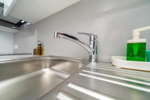 New 2 bedroom flat in Aglantzia في Aglantzia: حوض المطبخ مع زجاجة خضراء عليه