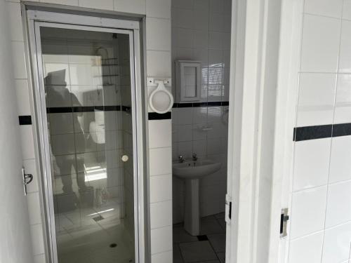 a bathroom with a sink and a glass door at Sagrada Guest House in Mthatha