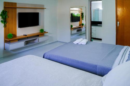 a bedroom with two beds and a flat screen tv at Pousada sousa Residencial Qrt 3 in Sousa