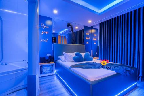 a blue bedroom with a bed and a bath tub at Motel Emoções in Nogueira da Regedoura