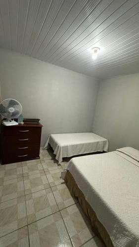 - une chambre avec deux lits et une commode avec un ventilateur dans l'établissement Beach Loft, à Vila Velha
