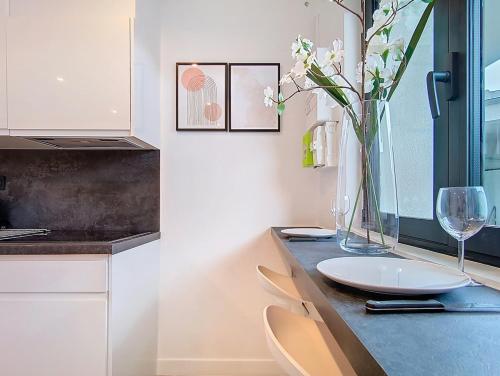 eine Küche mit einem Tisch mit einer Blumenvase in der Unterkunft Be Happy - Appartement central in Argenteuil