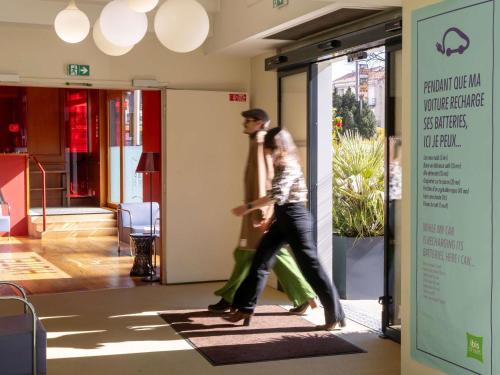 Ein Mann und eine Frau gehen den Flur entlang in der Unterkunft ibis Styles Le Puy en Velay in Le Puy en Velay