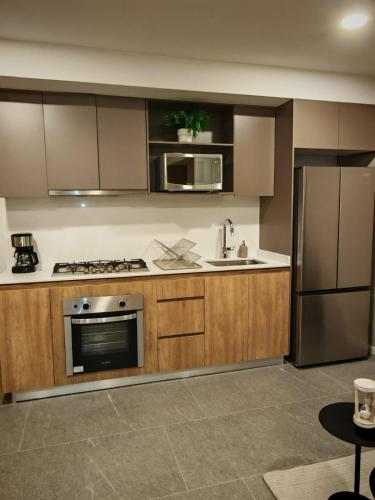 a kitchen with wooden cabinets and a stainless steel refrigerator at Loft Centro Zapopan in Guadalajara