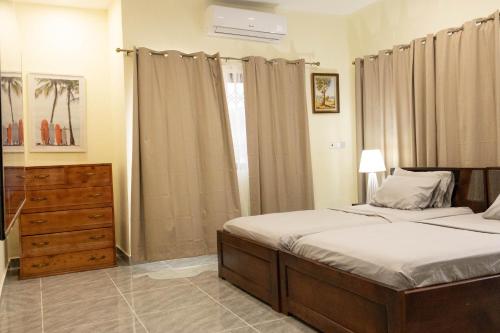 een slaapkamer met een bed, een ladekast en een raam bij BethelAirBnB in Winneba