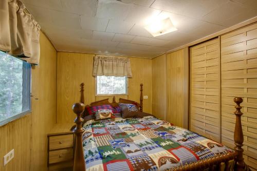 a bedroom with a bed with a quilt on it at Little Manistee Riverfront Cabin with Fire Pit! in Irons