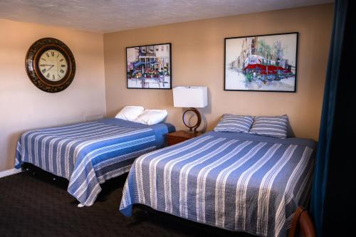 a hotel room with two beds and a clock on the wall at Yellowstone Motel in Idaho Falls