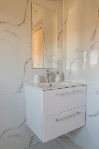 a white bathroom with a sink and a mirror at Domki u Wojtka in Grywałd