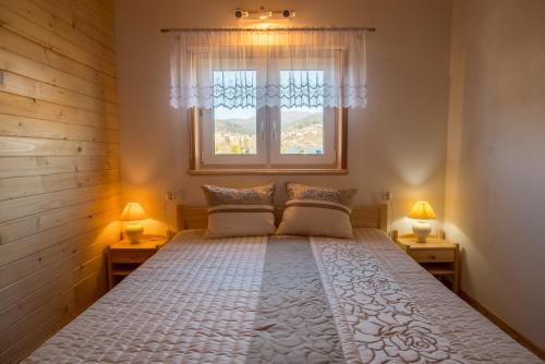 a bedroom with a large bed with two lamps at Domki u Wojtka in Grywałd