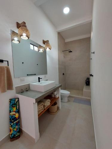 a bathroom with a sink and a mirror and a toilet at Villa BotaNICA guest house in San Juan del Sur
