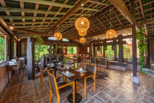 Coração da Terra Praia do Rosa في برايا دو روزا: غرفة طعام مع طاولات وكراسي ونوافذ