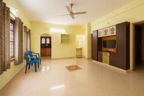 Bhakti Bliss Homestay - Spacious 2bhk AC Apartment near Padmavati Ammavari Temple in Tirupati في تيروباتي: غرفة معيشة مع كراسي زرقاء وتلفزيون