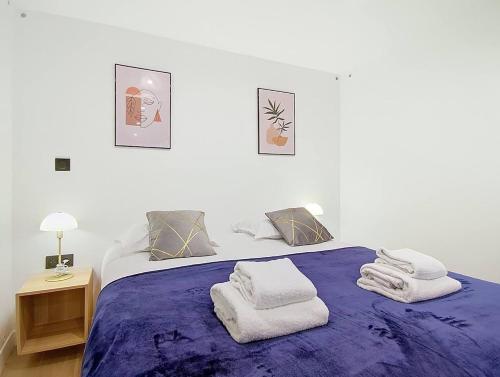 ein Schlafzimmer mit einem lila Bett mit Handtüchern darauf in der Unterkunft Suite Feel Good - Appartement in Argenteuil