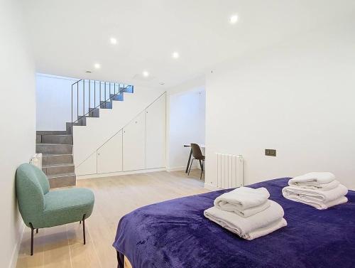 ein weißes Zimmer mit einem Bett und einem blauen Stuhl in der Unterkunft Suite Feel Good - Appartement in Argenteuil