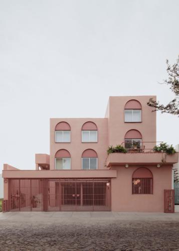 a pink building with a fence in front of it at Casa Rosa by Domi Housing in Querétaro