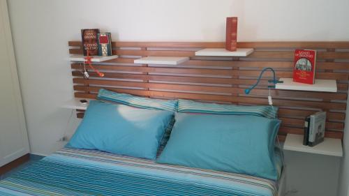 een bed met een houten hoofdeinde en 2 blauwe kussens bij Residenza del Mare & SPA in San Vito lo Capo