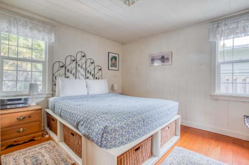 a bedroom with a large bed and two windows at Cathys Cottage in Cannon Beach