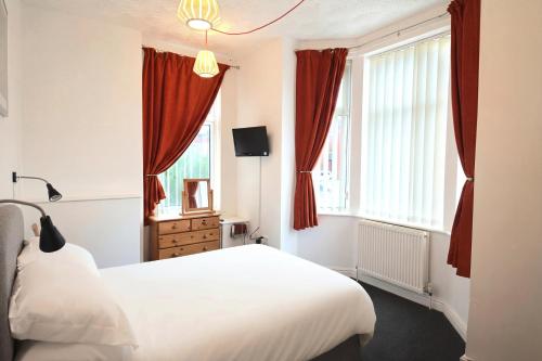 a bedroom with a white bed and red curtains at 3 Person Apartment with Priv Entrance and Carpark in Stockport