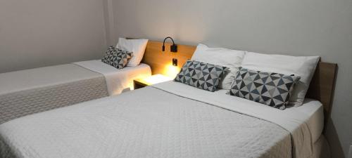 2 camas en una habitación pequeña con lámpara en Abudi Hotel, en Cuiabá
