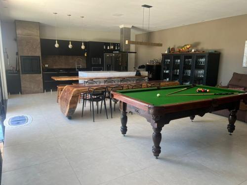 uma sala de estar com mesa de bilhar e cadeiras em Linda casa com piscina - locação temporada em itapoá sc em Itapoa