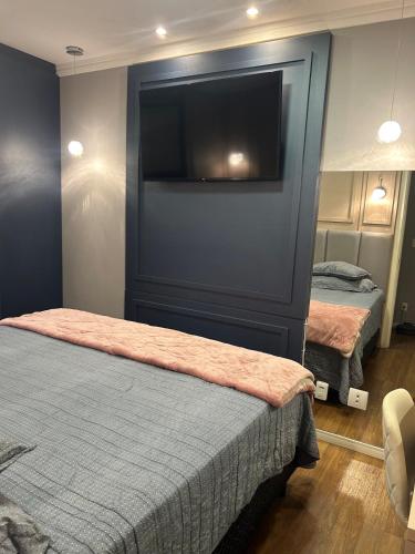 a bedroom with two beds and a flat screen tv at Apartamento Alto Padrão in Porto Belo