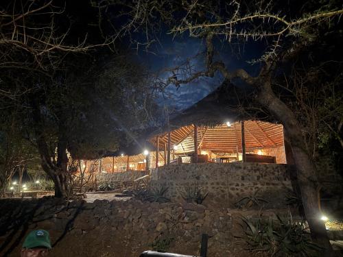 une maison la nuit avec un mur de pierre dans l'établissement Burko Luxury Camp & Lodge, à Arusha