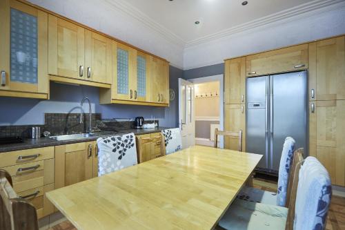 a kitchen with a wooden table and a refrigerator at Hayy Contractor House 5 Bedroom Huddersfield Sleeps 18 in Huddersfield