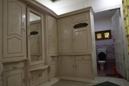 a bathroom with white cabinets and a toilet at Munnar Stays - Homestay & Resort in Devikolam