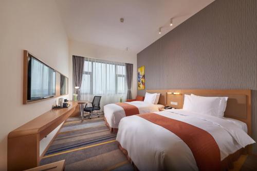 ein Hotelzimmer mit zwei Betten und einem Schreibtisch in der Unterkunft Holiday Inn Express Chengdu Huanhuaxi by IHG-Near Jinsha Site Musem,Near Wuhou Temple Museum,Welcome drinks,Free gym,Free self-service laundry in Chengdu