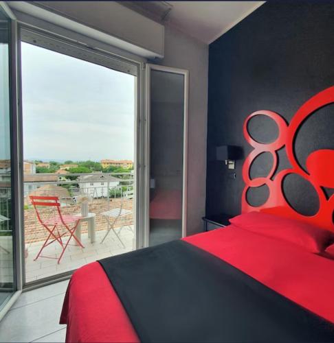 a bedroom with a red bed and a large window at Coelho Boutique Hotel in Gatteo a Mare
