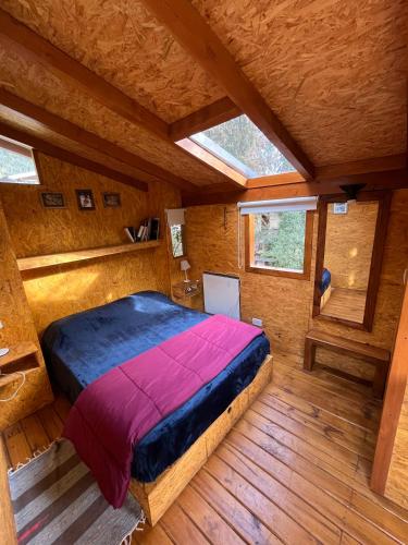 a bedroom in a log cabin with a large bed at Los Coihues camping & hostel in San Carlos de Bariloche