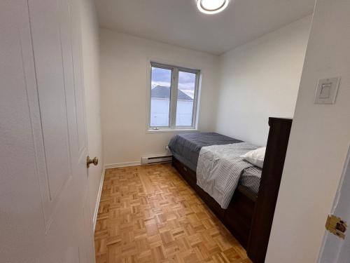 Charming Family Home in Peaceful Laval في لافال: غرفة نوم صغيرة بها سرير ونافذة