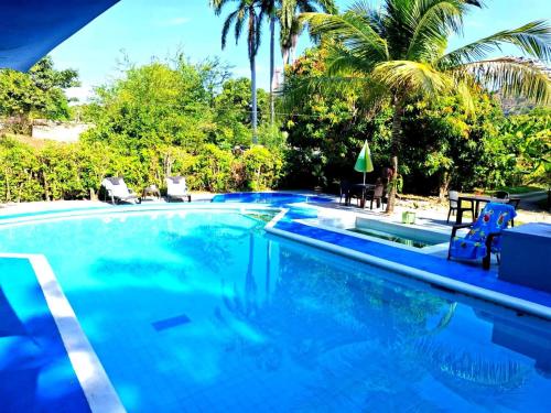 a swimming pool with blue water and palm trees at Casa siboney in Estación El Salto