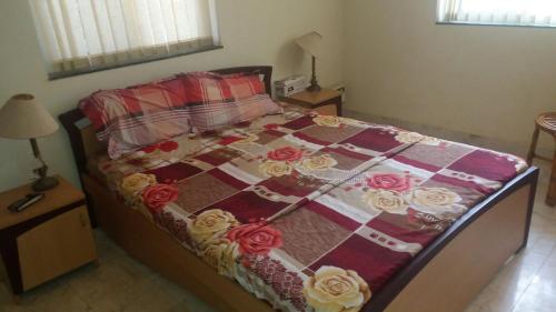 a bed with a quilt with roses on it at Justin Apartment in Varca