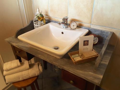 a bathroom sink with a clock on a counter at Cantina Anzivino - Affittacamere in Gattinara