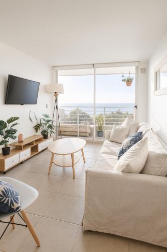 un soggiorno bianco con un divano e un tavolo di Depto Ocean View Algarrobo Norte - Piscina, WiFi y Estacionamiento ad Algarrobo