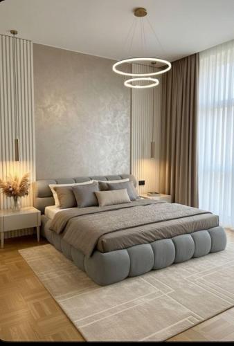 una camera da letto con un letto grande con un lampadario di Gf Apartment a Pristina