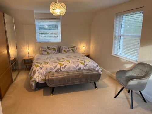 a bedroom with a bed and a chair and two windows at Swn yr Coed in Sennybridge