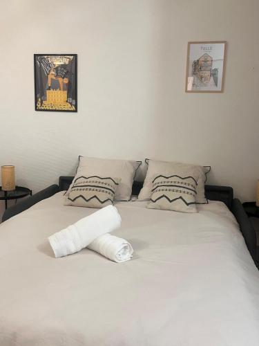 a white bed with two towels on top of it at Studio Excellence Tulle in Tulle