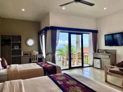 a bedroom with two beds and a television and a balcony at Mejore Beach Hotel in Amed