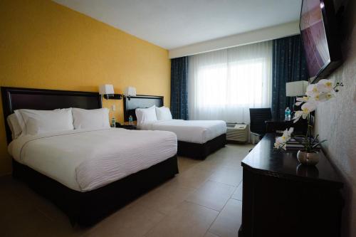 a hotel room with two beds and a desk at Hotel Katuxlan in Campeche