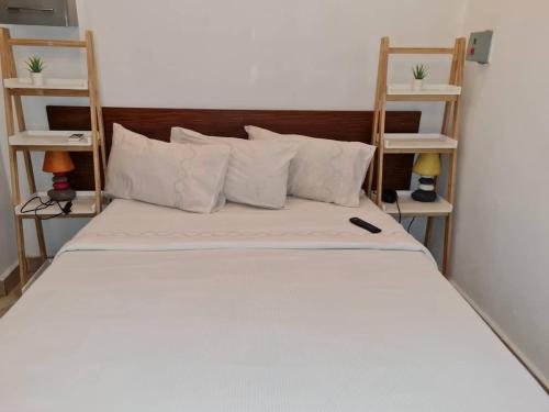 Una cama con sábanas blancas y almohadas en una habitación. en 2 Bedroom Appartement in the City, en Kinshasa