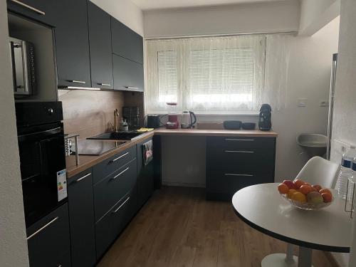 圣路易Corner of Serenity的厨房配有黑色橱柜和一张带一碗水果的桌子